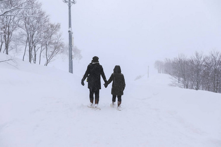 一对情侣手牵手在雪地上散步,日本/gala yuzawa照片