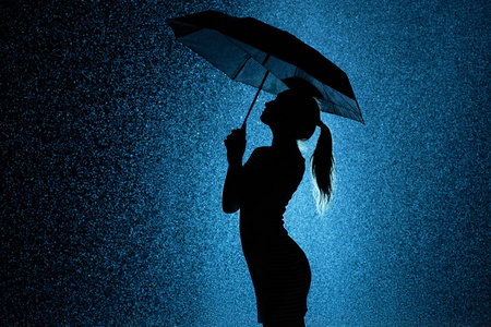 雨中撑伞少女的身影剪影照片
