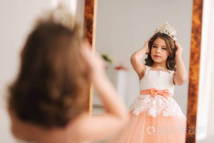 女孩戴上王冠.快乐的小公主照镜子