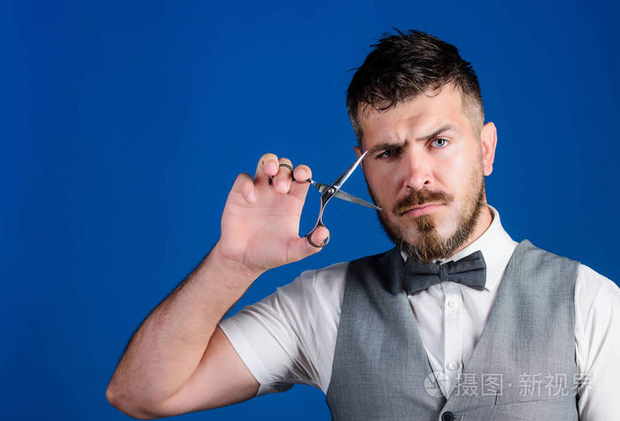 大胡子理发师拿着剪刀剪头发.理发店服务理念.商人严把脸拿着剪刀.