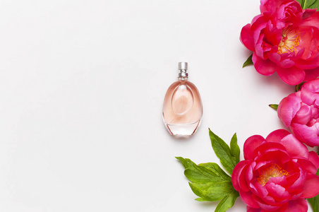香水瓶和粉红色的牡丹花在浅灰色背景上俯视平铺复制空间.