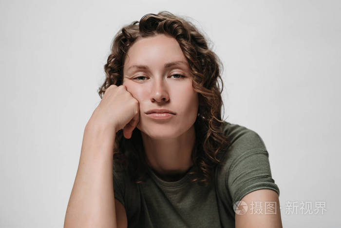 不悦疲倦困倦的卷发女人撑着他的脸颊看着