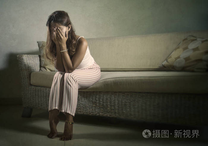 年轻的悲伤和沮丧的女人穿着睡衣在家里的沙发上哭泣绝望的感觉沮丧和