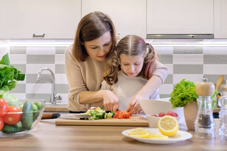 家庭烹饪健康的家常饭.母女俩在家厨房切菜做沙拉照片