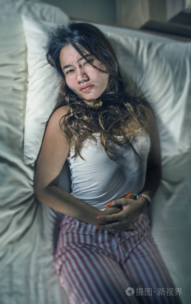 年轻迷人悲伤的20多岁女性躺在床上脸上有剧烈的疼痛