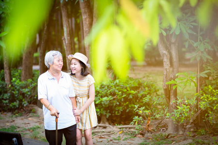 亚洲小女孩用手杖搀扶老人,公园里幸福微笑的奶奶和孙女,老年人步行