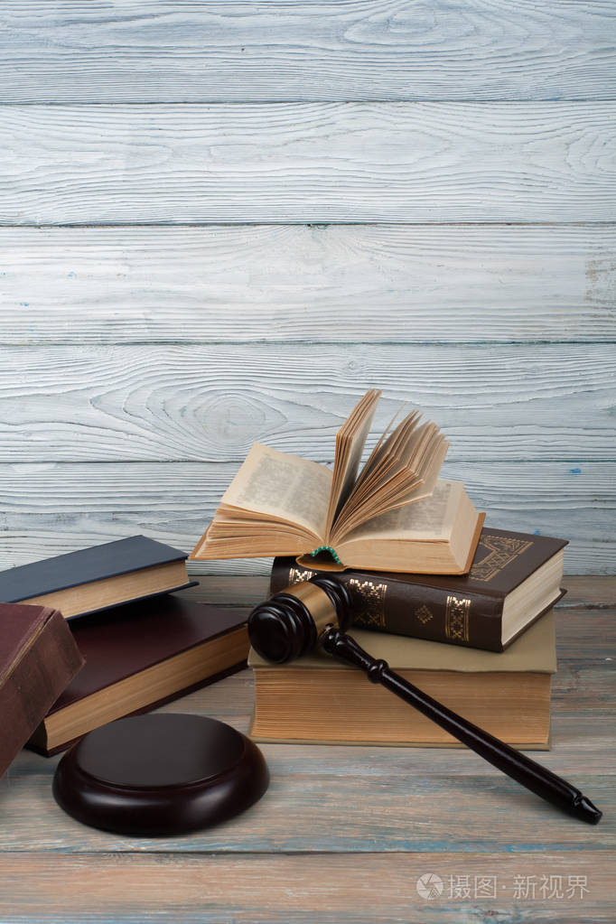 的法律书与木制法官木槌放在法庭或执法办公室的桌子上孤立的白色背景