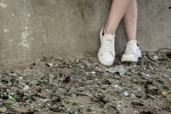 青少年的脚在一堆碎玻璃和碎片中.问题青少年与