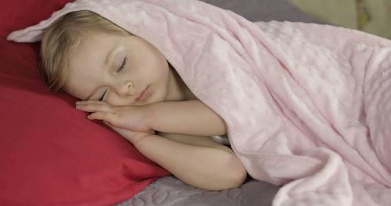 可爱的宝宝睡在家里的床上.在晨光中睡觉的小女孩照片