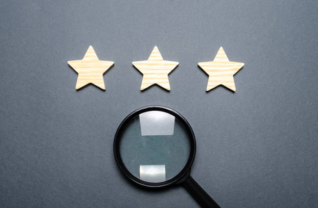 标准费率三颗星和一个放大镜在灰色的背景上.餐厅或酒店的等级和状态.