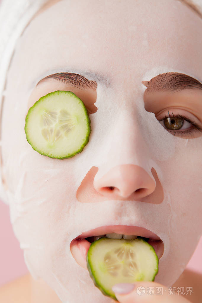 一位年轻漂亮的女士正在用粉底黄瓜在脸上敷面膜