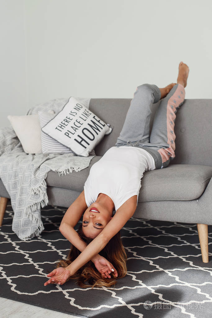 头朝下躺在灰色沙发上休息的美女可爱的女孩在慵懒的日子里在舒适的家