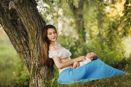 慈爱的母亲抱着刚出生的婴儿.美丽的妈妈带着一个可爱的新生儿在户外.