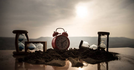 一个沙漏在明亮的蓝色天空前面,浮肿的白云掠过.时间概念.照片
