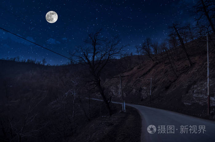 月圆之夜穿过森林的山路夜有大月的乡村公路夜景长快门照片