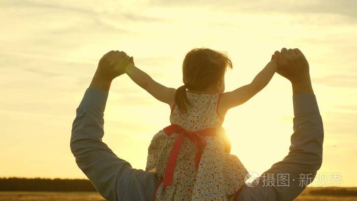 在夕阳的余晖中父亲扛着女儿走着爸爸背着他心爱的孩子的肩膀走过田野