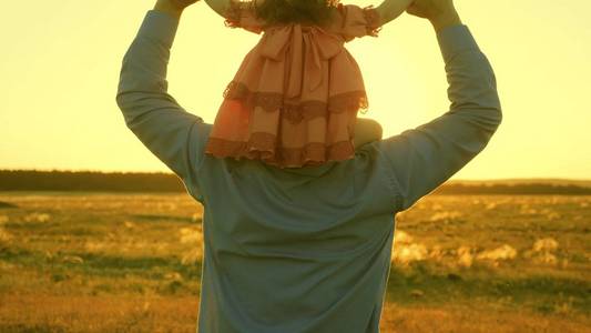 在夕阳的余晖中,父亲扛着女儿走着.