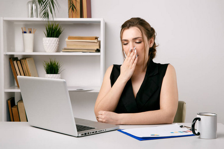 早上又累又困的女人在上班.在办公室喝杯咖啡.照片