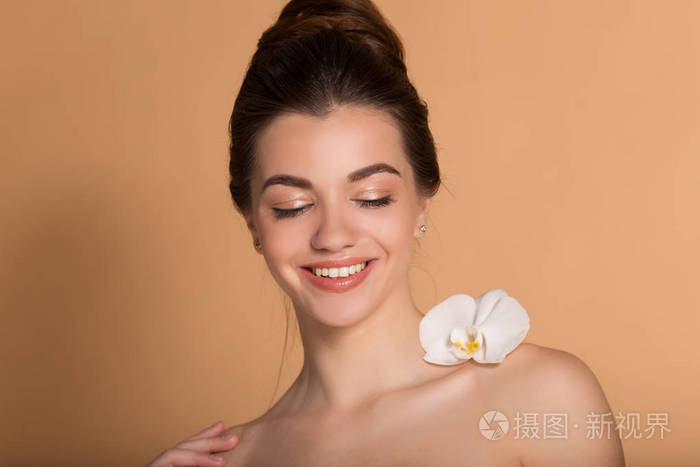 一张年轻漂亮女孩的特写肖像,皮肤完美无瑕,肩上挂着白色兰花.