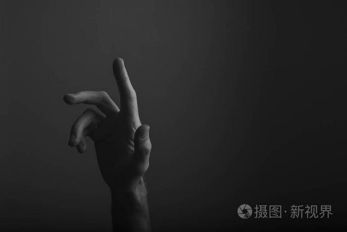 一只雄性的手在黑暗的背景下指指点点选择触摸