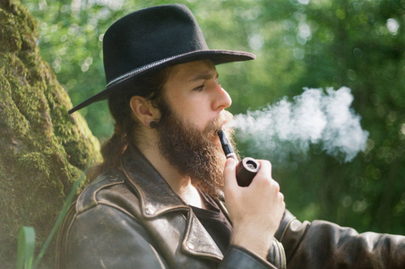戴帽子的大胡子男人抽烟斗的肖像照片