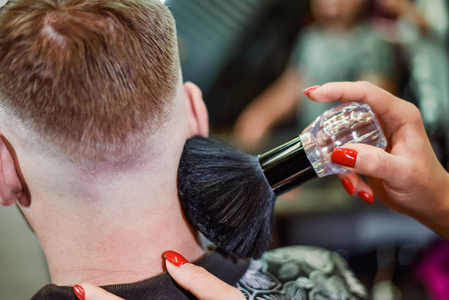 女理发师剪完头发后用刷子清除头发残留物照片