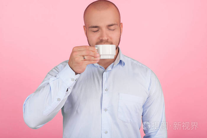从已经升到鼻子的杯子里闻咖啡.站在粉红色背景前