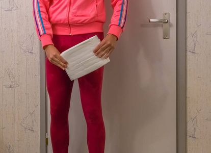 成人女士尿失禁,穿着湿腿裤的年轻女士拿着白色成人尿布,尴尬的健康