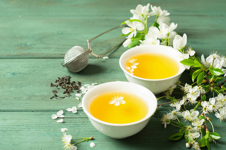 花茶加工一杯芳香的花茶,木质背景上有白色的花瓣.选择性聚焦.