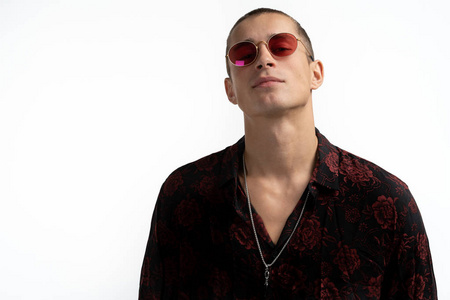 帅气的休闲男子,短发,戴着红色太阳眼镜,在白色背景下的摄影棚里摆