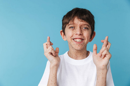 image of happy boy 10-12y with freckles keeping fingers crossed