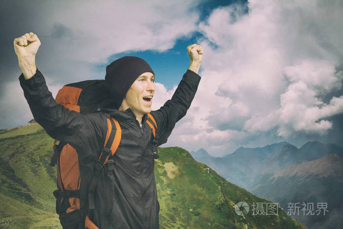 年轻的徒步旅行者高举双手站在山顶上大声喊叫,侧视.照片-正版商用图
