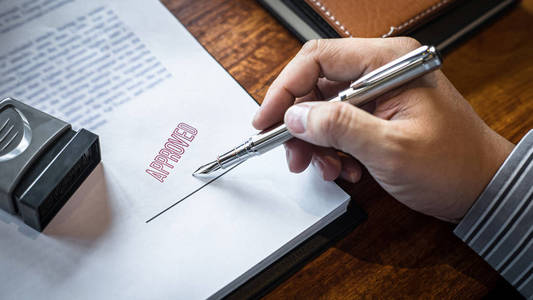 商人在纸质文件上签字盖章照片