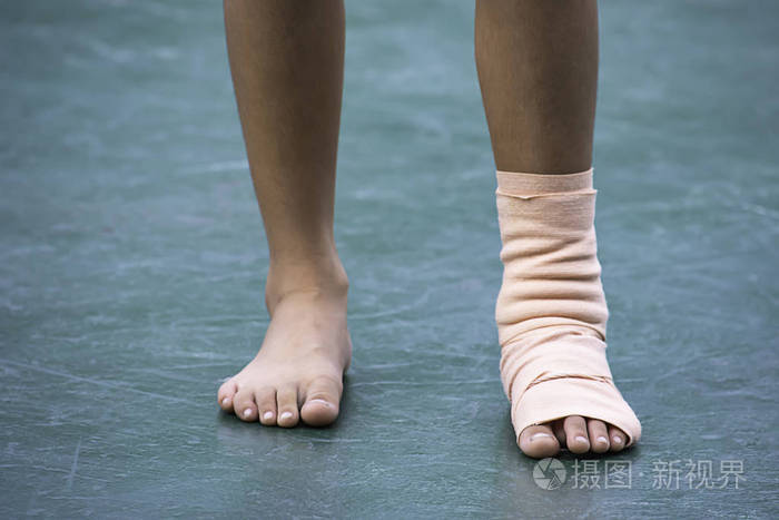 纱布绷带围绕脚踝男孩和腿部发炎肿胀在绿色背景