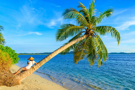 戴着传统亚洲帽子的女人在热带海滩上放松在夕阳的背光下真实的人印度