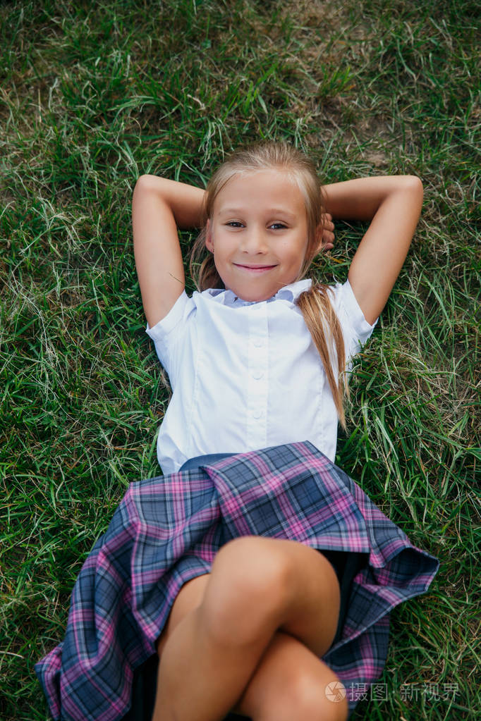 可爱的小学女孩躺在草地上照片-正版商用图片2jzcbm-摄图新视界