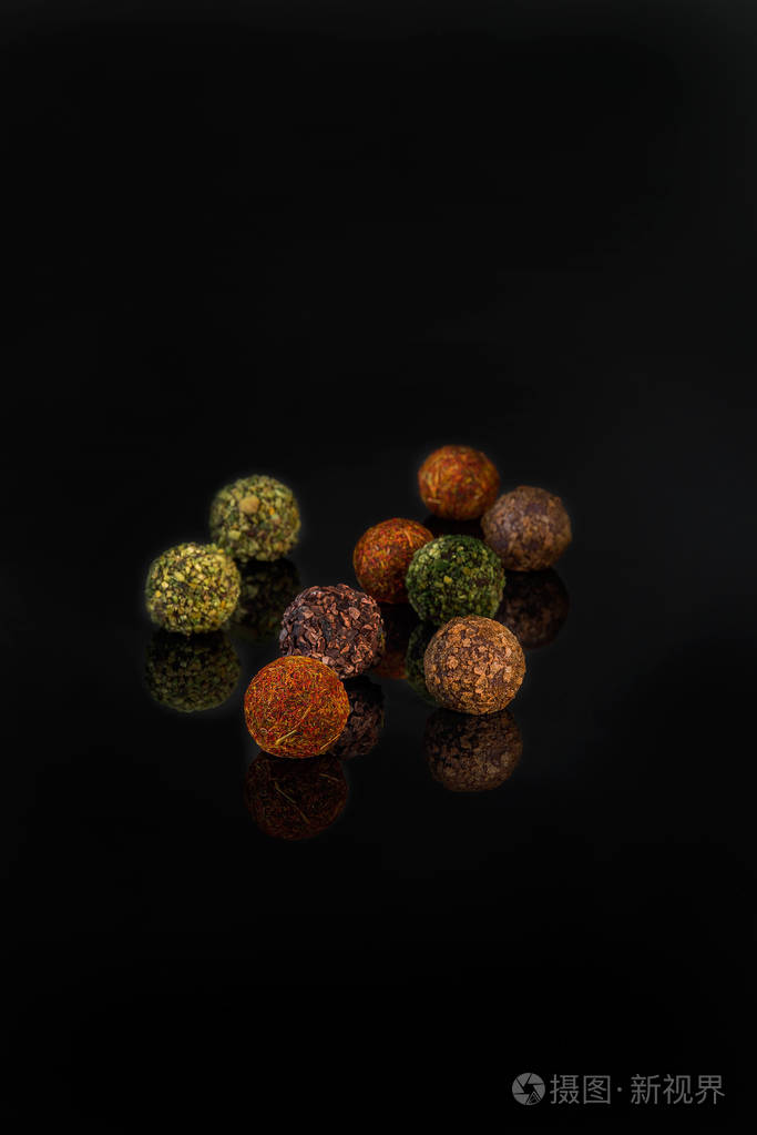 黑色背景上撒上香料的巧克力圆形糖果