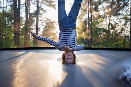 可爱的小男孩在蹦床上跳来跳去翻跟头照片