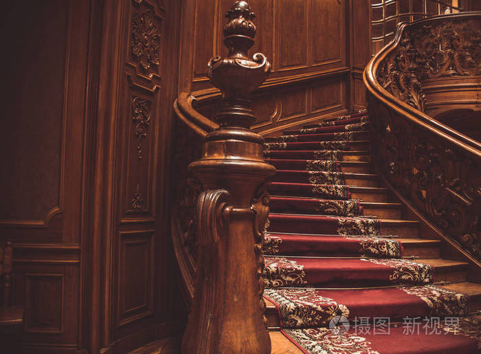 旧的螺旋木楼梯，室内有复古栏杆，铺着地毯。宫殿内豪华的木雕内饰。罕见的建筑。复制空间