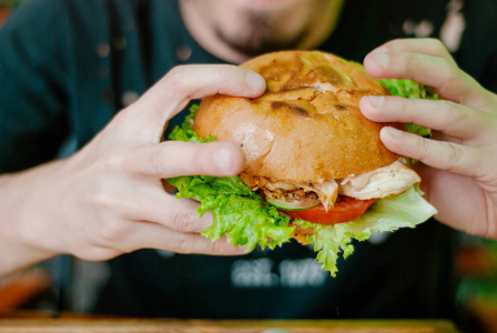 一个男人在餐馆里吃汉堡包,他饿了,而且吃得很香.选择性聚焦照片