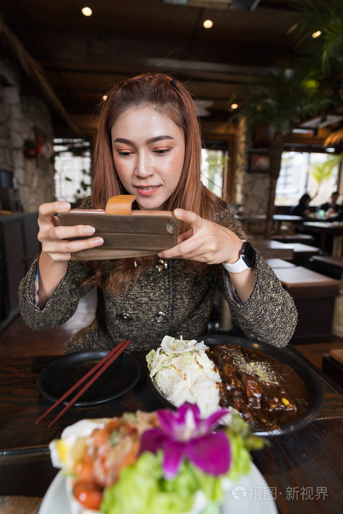 一位女士在餐厅用智能手机拍照