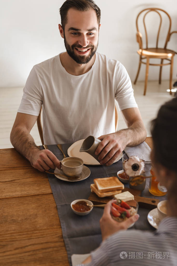 图为一对快乐的黑发情侣在餐桌边吃饭而h