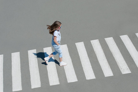 夏天在街上的人行横道上,穿时装的小女孩横穿马路.从顶视图.
