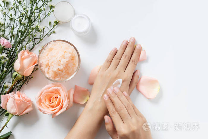 天然护肤理念女士在白色的背景上用手抹上白色的面霜用一罐化妆品盐