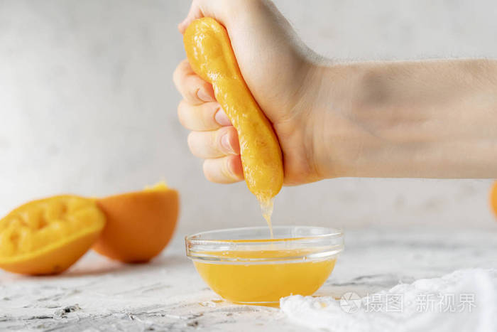 人们赤手空拳地在玻璃杯里挤新鲜的橙汁健康的饮料