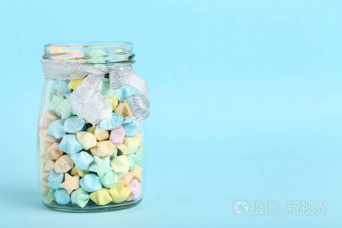 蓝色背景玻璃罐中彩色纸星星