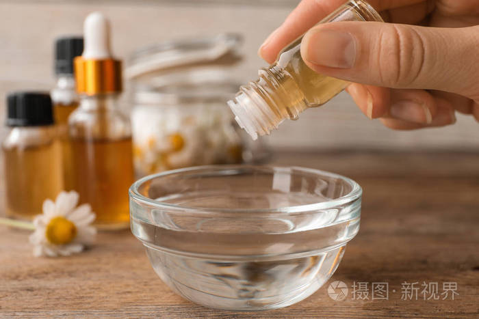 女人把精油滴到桌子上的碗里特写