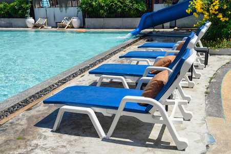 游泳池边带床垫的蓝色日光浴床图片