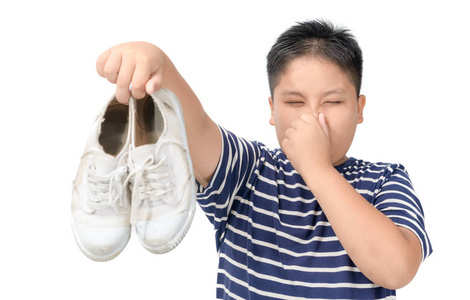 恶心的胖男孩拿着一双臭鞋子照片