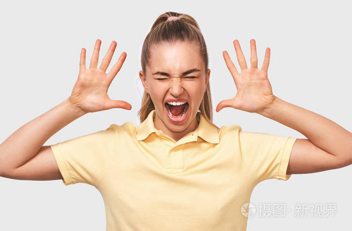 惊讶的金发女人双手比划大声尖叫穿着黄色t恤在白色工作室背景下摆
